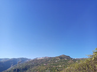 Open land plot with clear blue sky and distant hills in Trat.