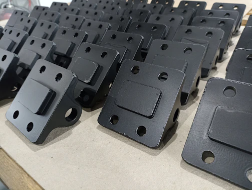 A close-up of shiny stainless steel corner brackets arranged neatly on a wooden surface.