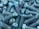 A collection of metal bolts with hexagonal heads and threaded bodies, arranged in a disordered pile. The bolts are predominantly blue with signs of wear and a rough texture.