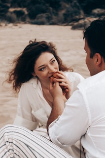 a man sitting next to a woman on a beach