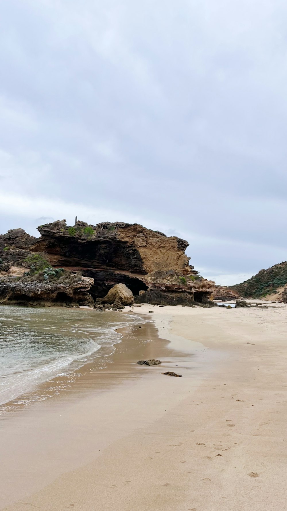 a sandy beach with a rock formation in the background