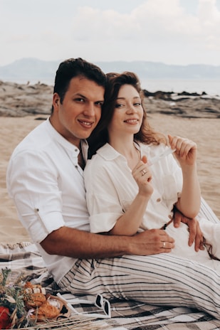A couple enjoying a private beach picnic on white sandy shores under swaying palm trees.