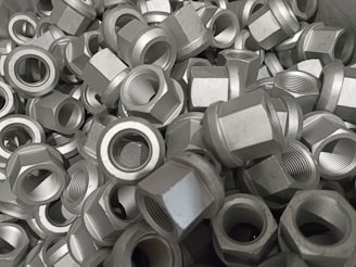 A pile of metallic hex nuts overlapping each other, showcasing their threaded interiors and outer hexagonal shape.