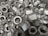 A pile of metallic hex nuts overlapping each other, showcasing their threaded interiors and outer hexagonal shape.
