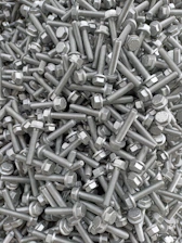 Close-up of industrial metallic nails and bolts piled in a rustic factory setting.