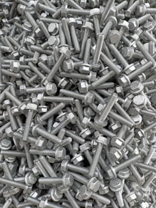 Close-up of industrial metallic nails and bolts piled in a rustic factory setting.