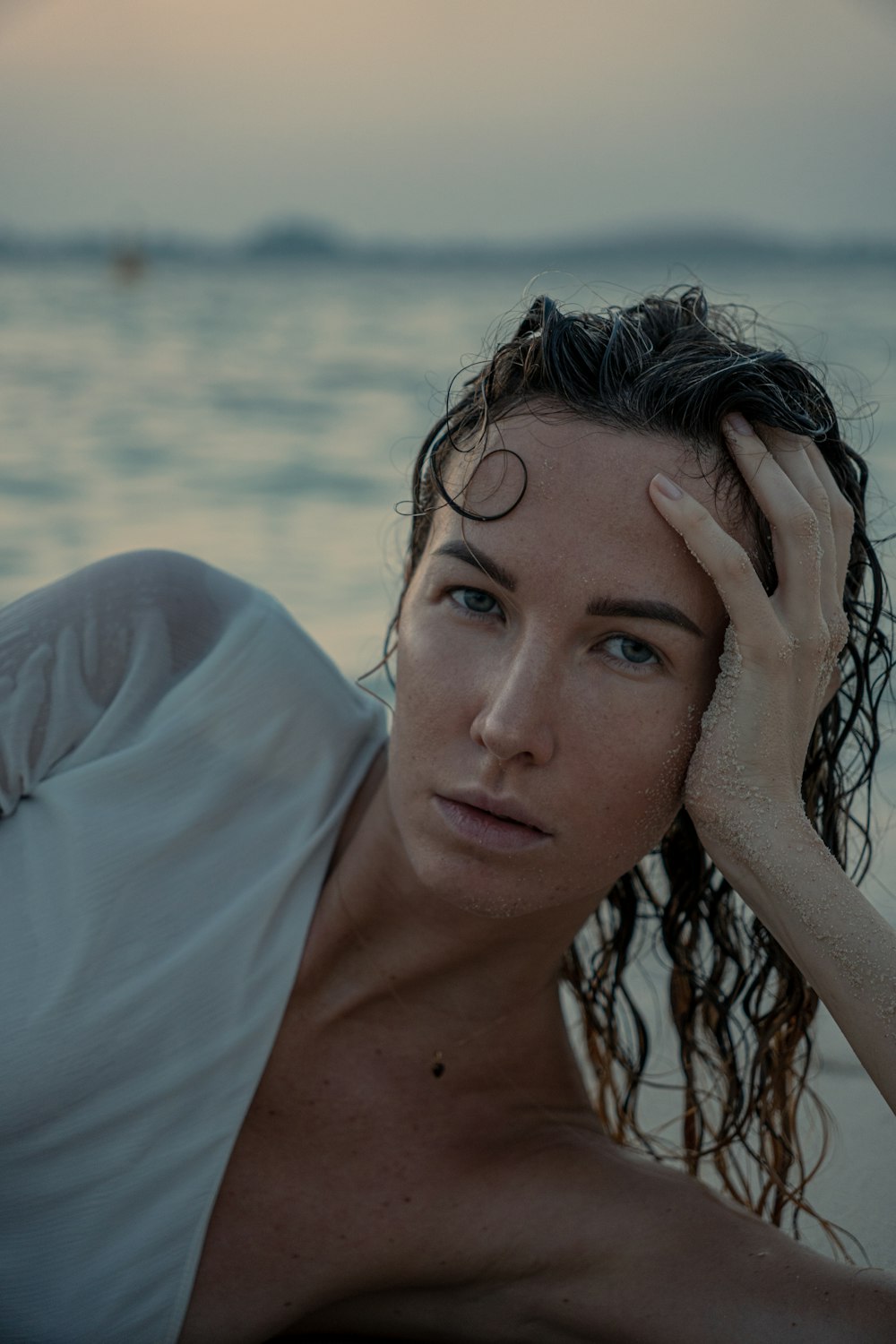 a woman laying on a beach next to the ocean