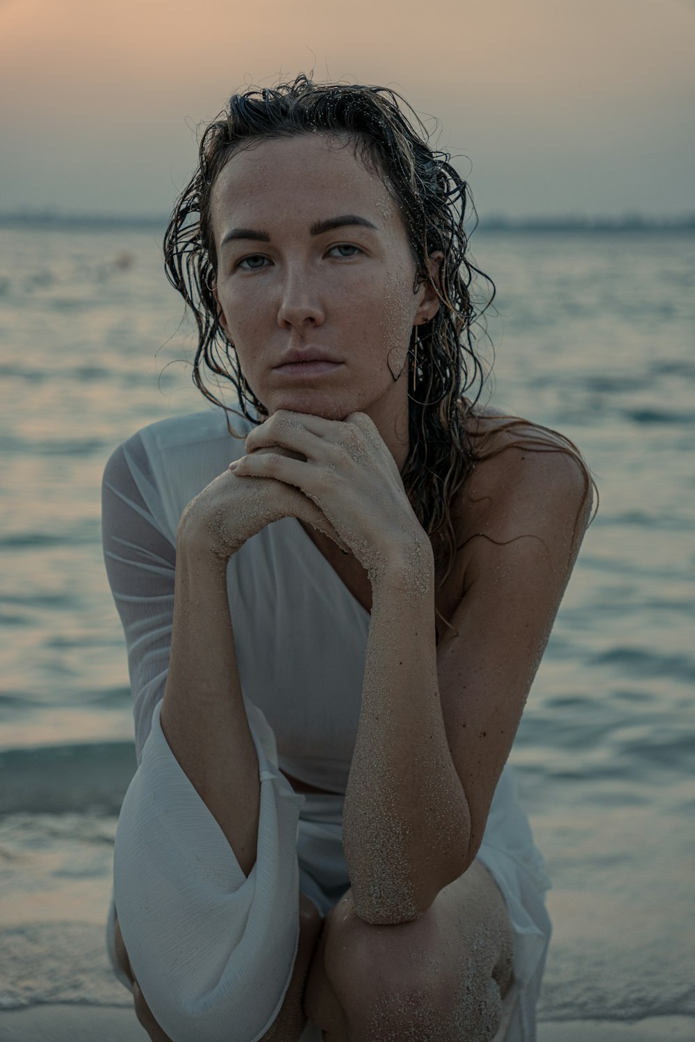 a woman sitting on a beach next to the ocean