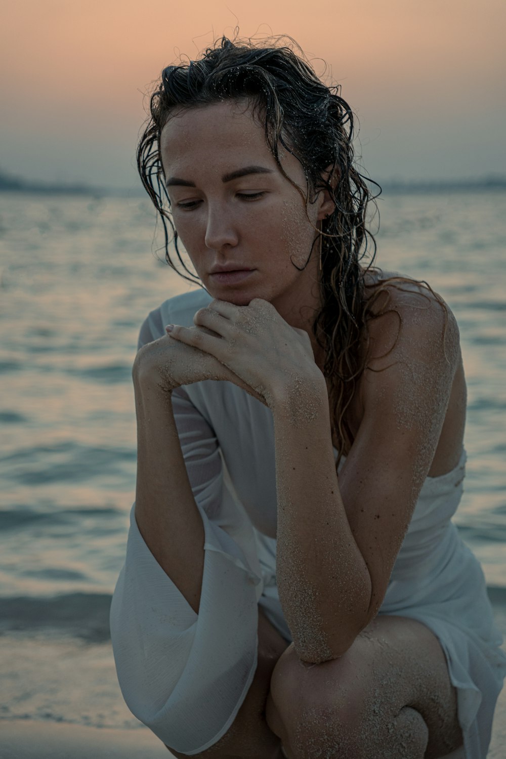 a woman sitting on a beach next to the ocean