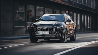 A stylish black SUV driving through a cityscape at night.