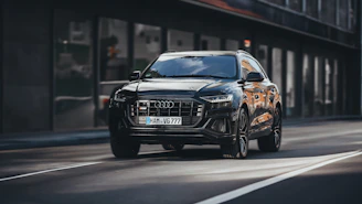 A sleek black SUV parked beside a sunlit city street, capturing the essence of modern urban travel.