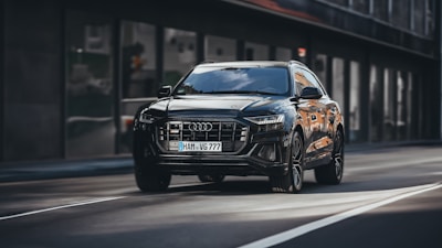 A stylish black SUV driving through a cityscape at night.