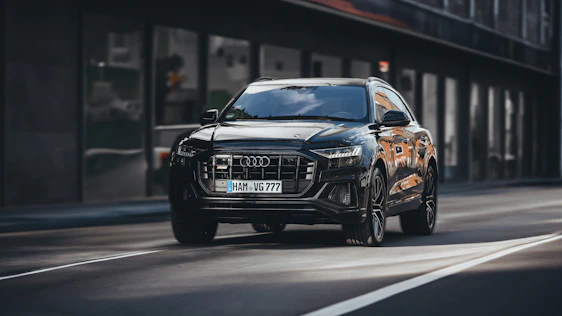 A sleek black SUV parked beside a sunlit city street, capturing the essence of modern urban travel.