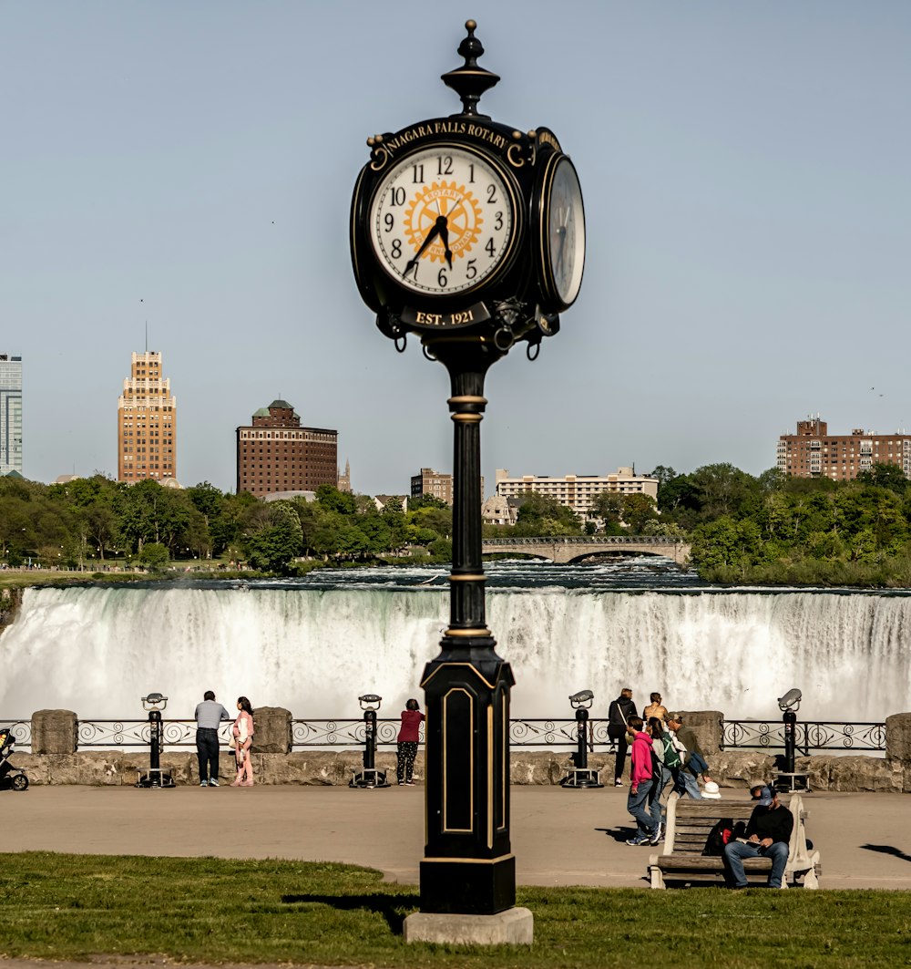 a clock on a pole in front of a waterfall