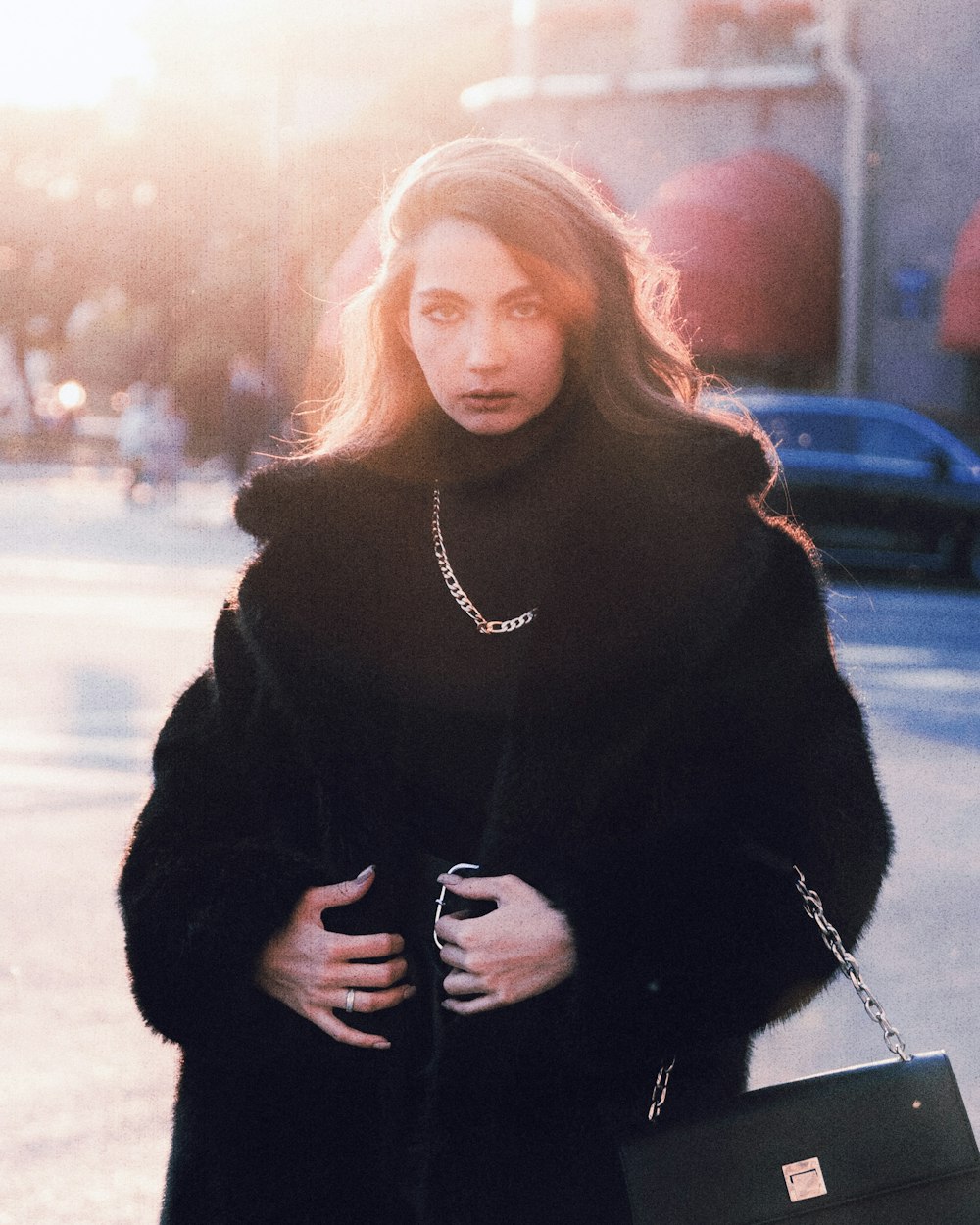 a woman in a black coat is walking down the street