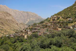 Traditional Sasak village houses nestled among lush green hills under a clear blue sky.