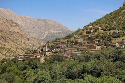 Traditional Sasak village houses nestled among lush green hills under a clear blue sky.