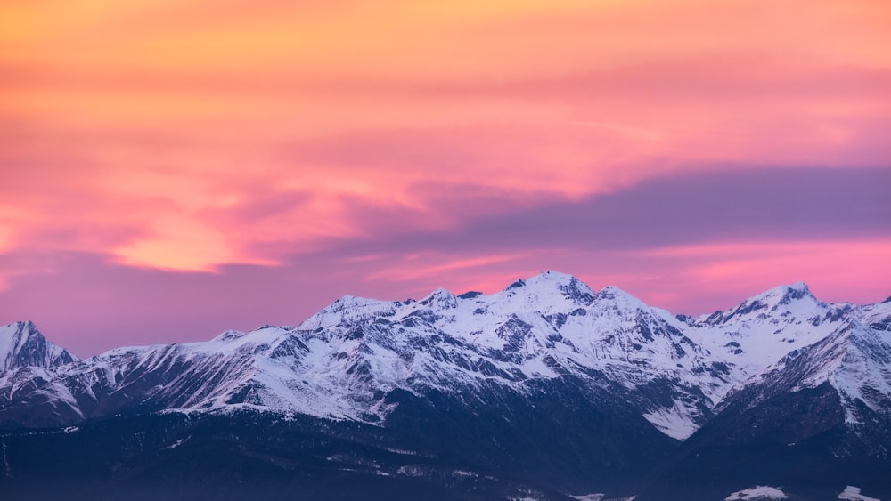 a view of a mountain range with a pink sky in the background