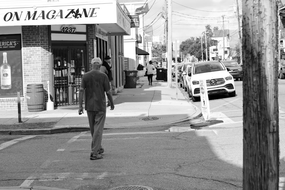 a man walking across a street in front of a store