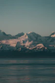 Snow-capped mountains reflecting in a still alpine lake at dusk.