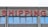A concrete building facade displays the word 'SHIPPING' in bold, red neon letters above a series of uniform, rectangular windows with reflective glass.