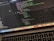 A close-up view of a laptop displaying code on the screen. The code editor is open on a dark-themed interface, showing lines of JavaScript with syntax highlighting. Below the screen, the keyboard of the laptop is partially visible. The laptop's dock at the bottom houses several application icons.