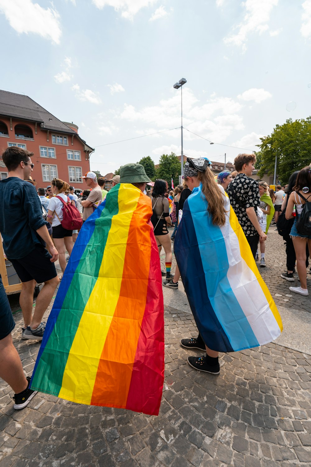 a group of people walking down a street holding a rainbow flag