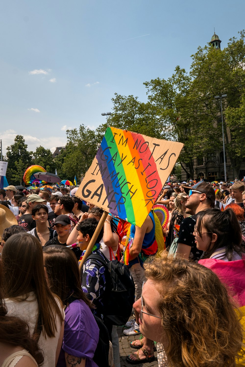 a crowd of people holding a rainbow colored sign