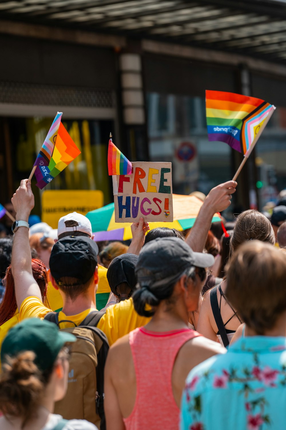 a group of people holding rainbow flags and a free hugs sign