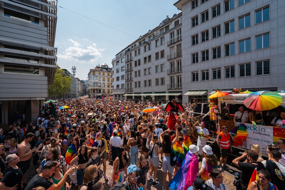 a crowd of people walking down a street next to tall buildings