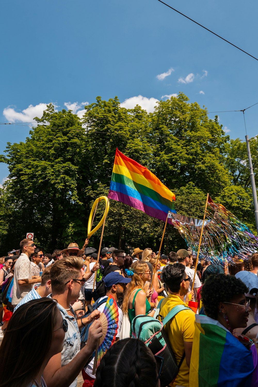 a crowd of people standing around a rainbow flag