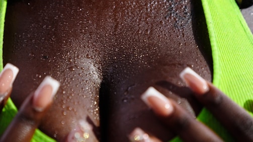 Close-up of a hand gently exfoliating skin with a traditional Moroccan kessa glove in a steamy hammam setting.