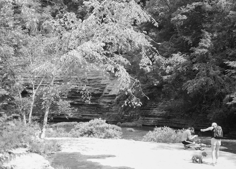 a man and a woman walking a dog in a wooded area