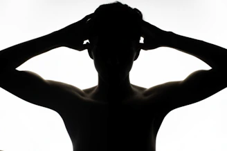 a silhouette of a man with his hands on his head