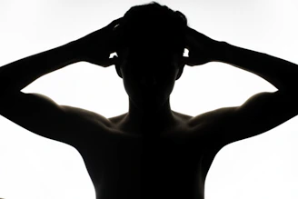 a silhouette of a man with his hands on his head
