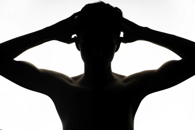 a silhouette of a man with his hands on his head