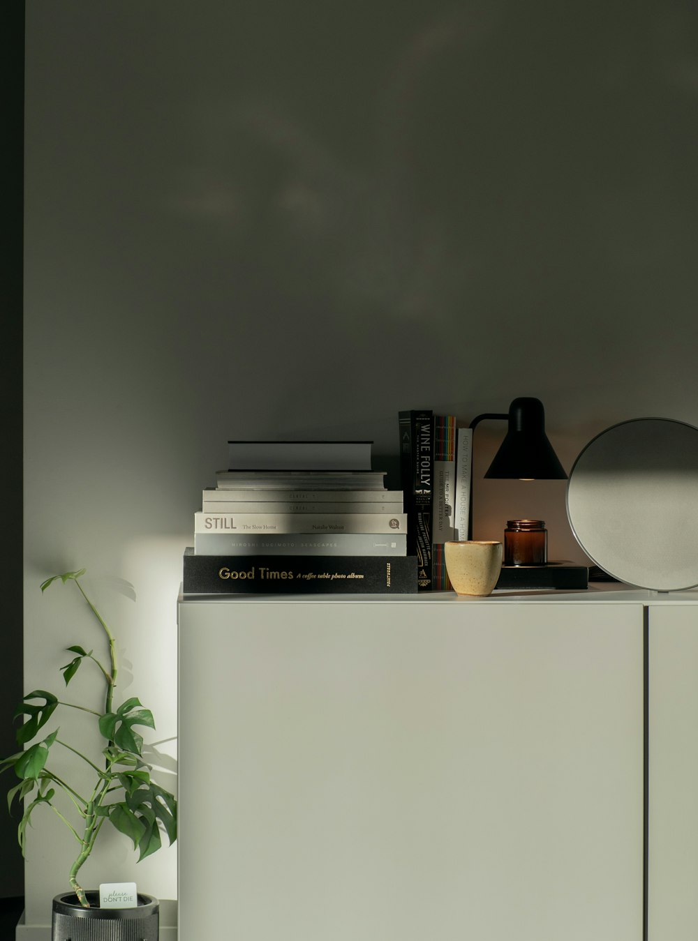 a white cabinet with books and a lamp on top of it