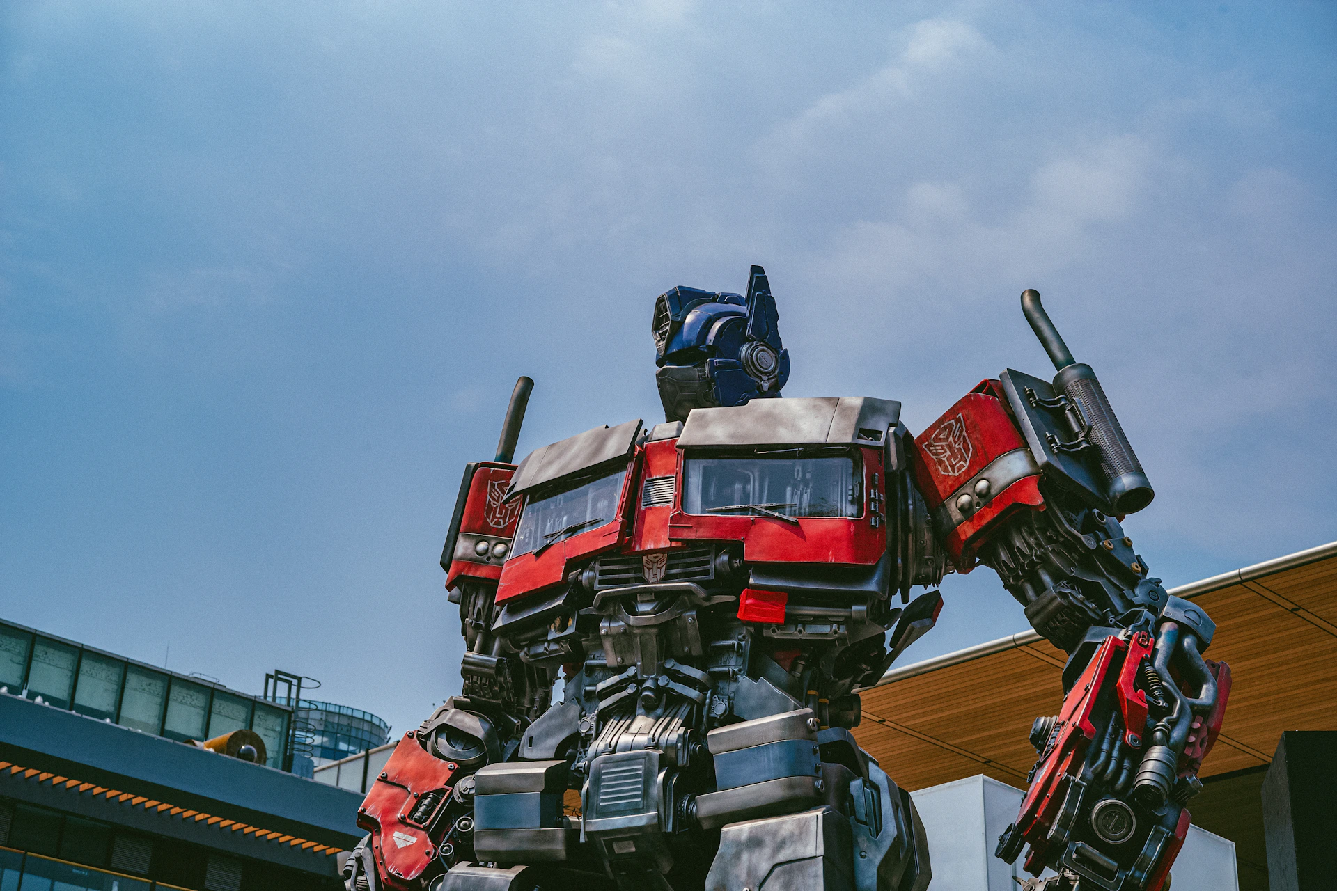 a red and black robot standing in front of a building