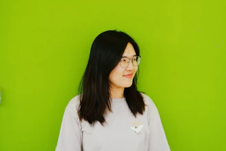 Anime character with aqua-green hair and big green eyes smiling warmly against a light green background.