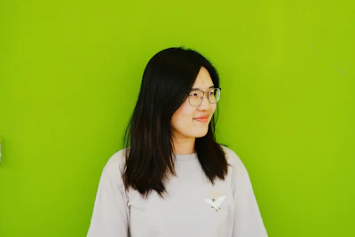 Anime character with aqua-green hair and big green eyes smiling warmly against a light green background.