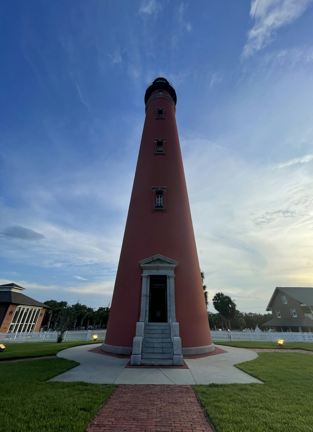 a red light house sitting on top of a lush green field