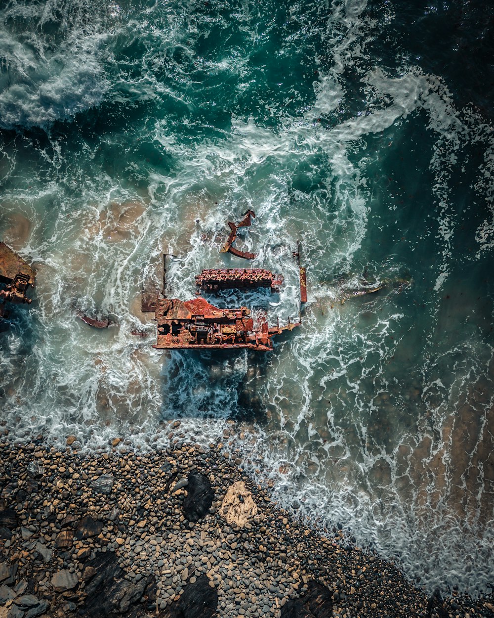 an aerial view of a rusty boat in the ocean