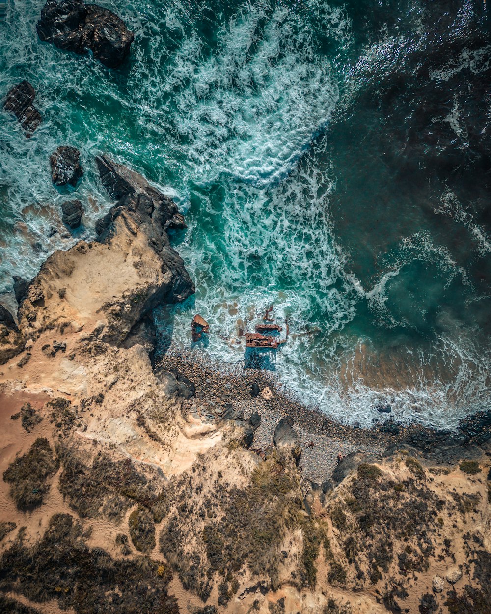 a couple of people standing on top of a cliff near the ocean