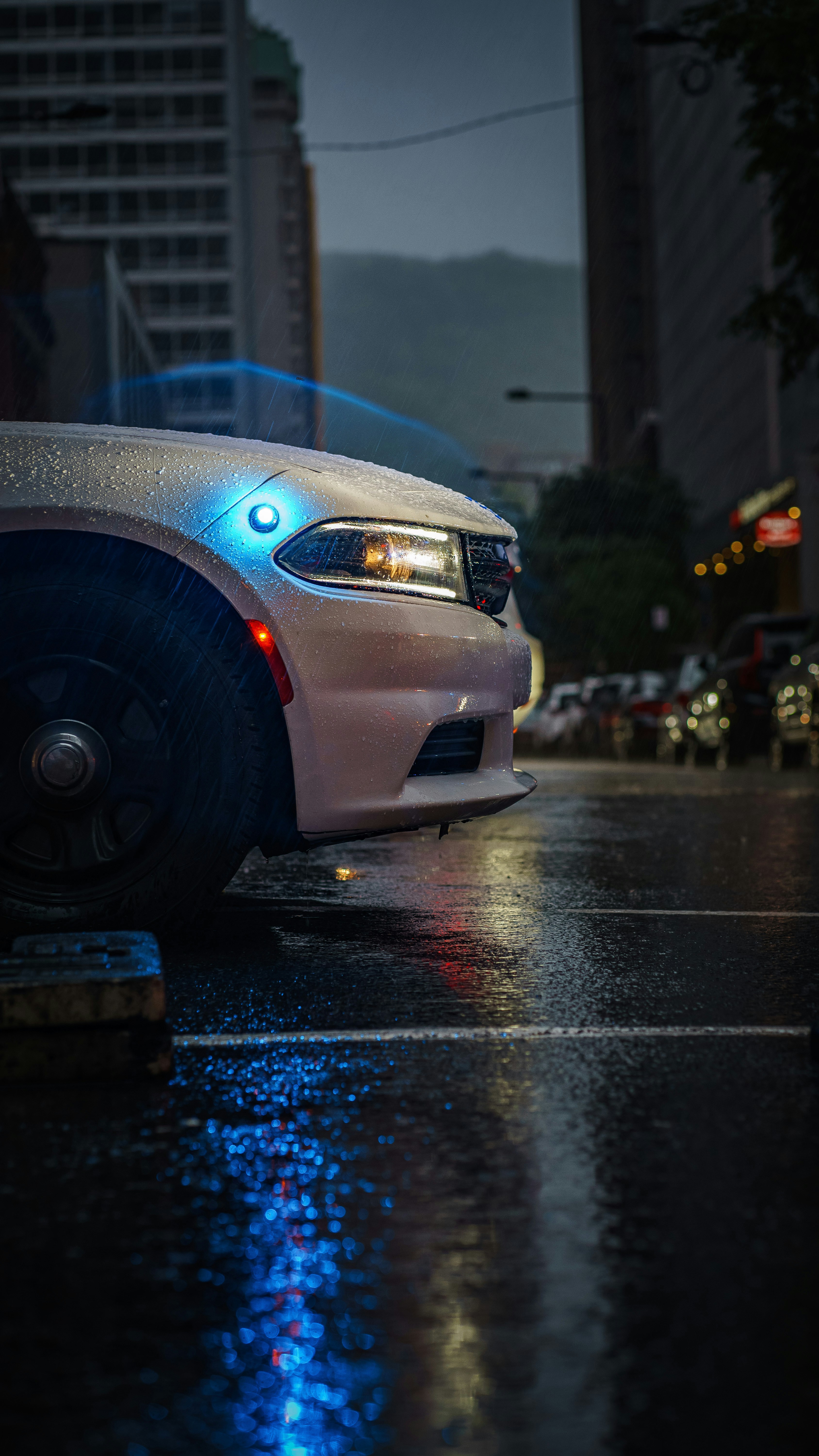 a police car parked on the side of the road in the rain