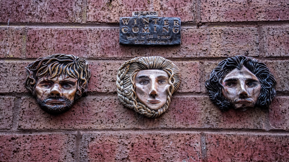 a brick wall with three metal faces on it