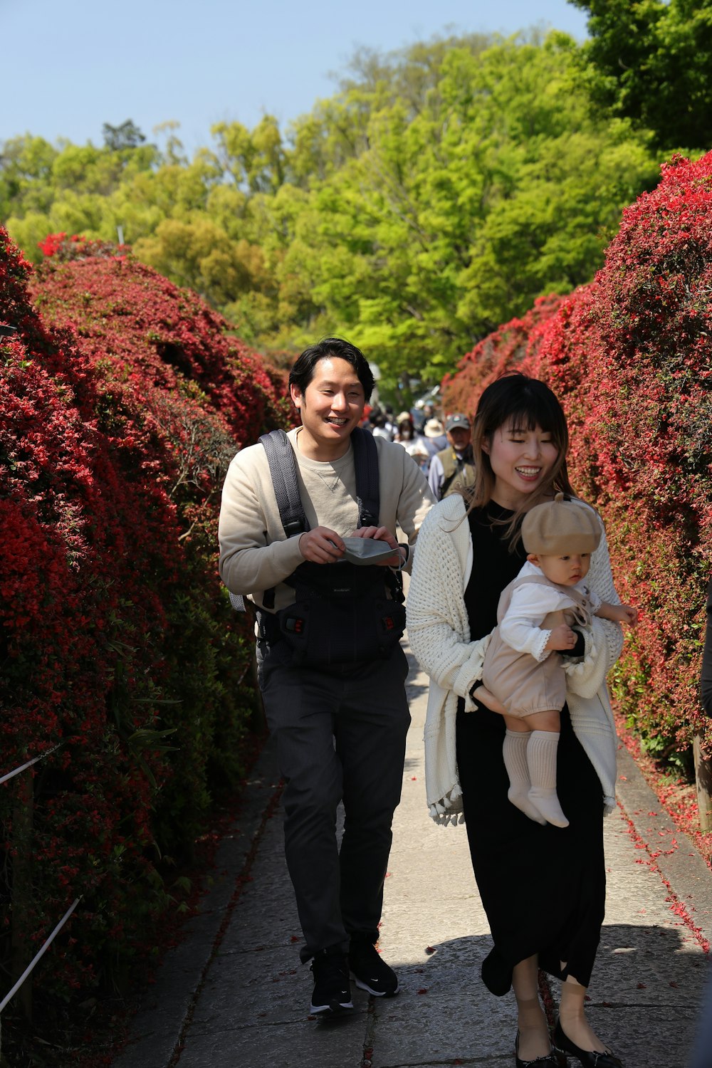 a man and a woman walking down a sidewalk holding a baby