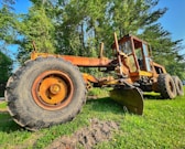 a tractor is parked in the grass near a tree