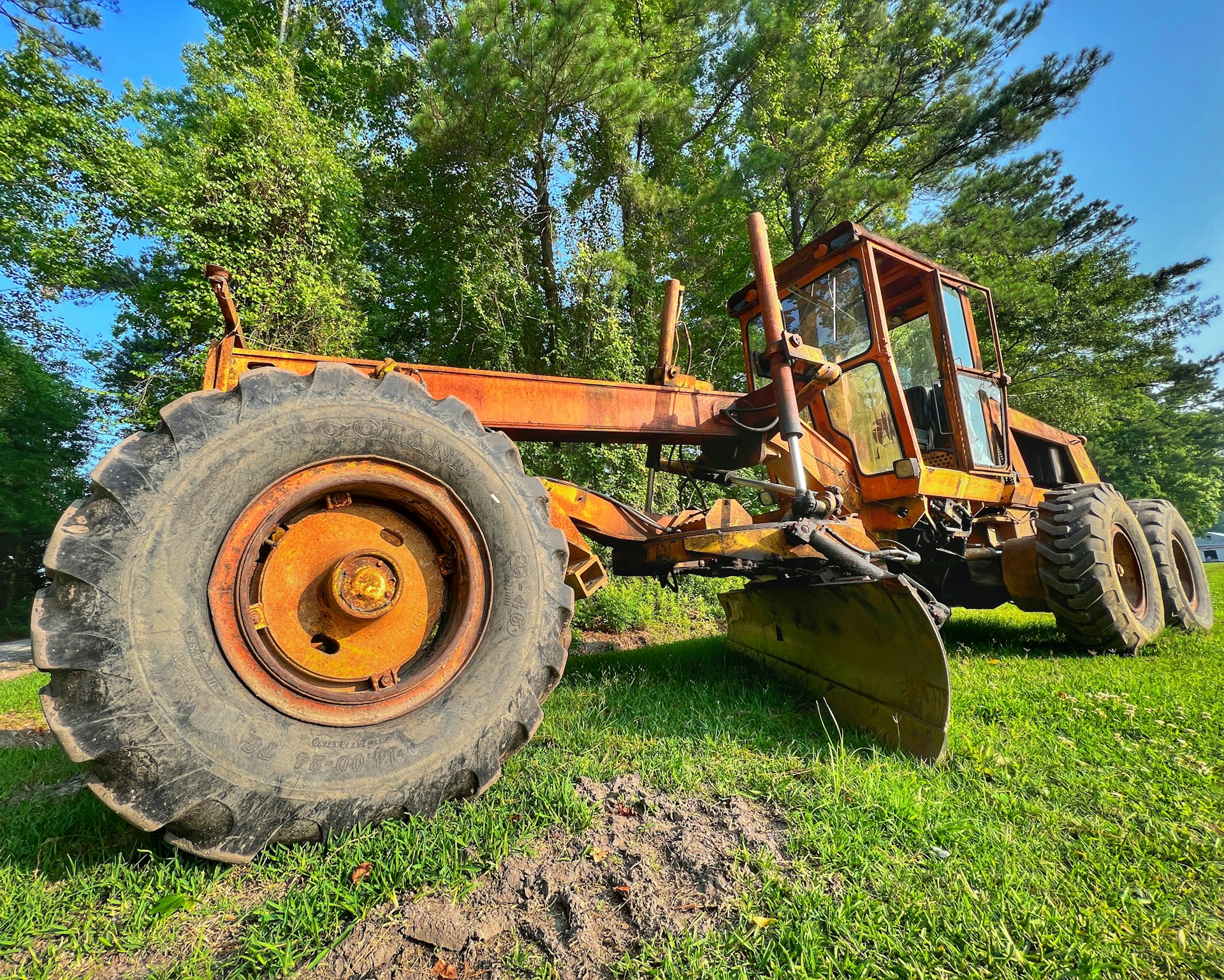 a tractor is parked in the grass near a tree