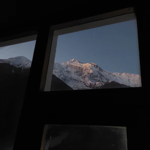 Snow-capped Himalayan peaks viewed from a cozy mountain lodge window.
