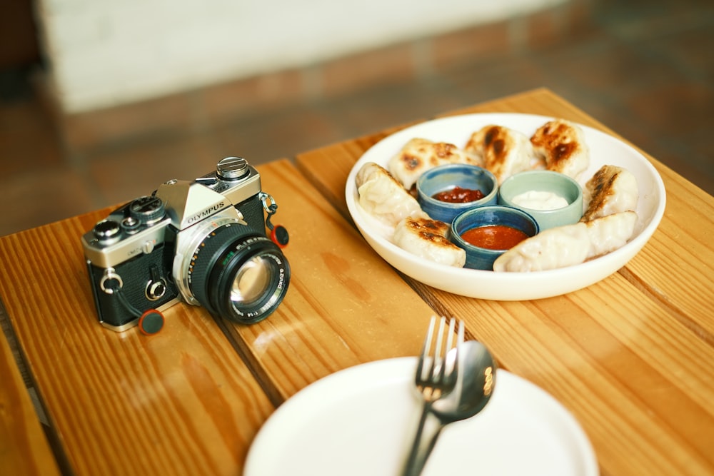 eine Kamera und ein Teller mit Essen auf einem Tisch